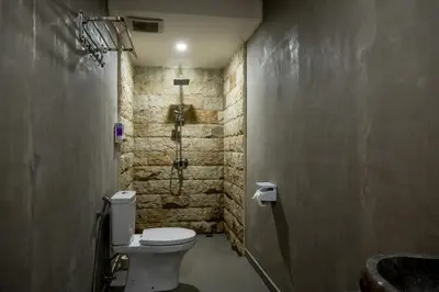 a bathroom with a toilet and a stone wall at Villa Inges 3 Seminyak in Seminyak