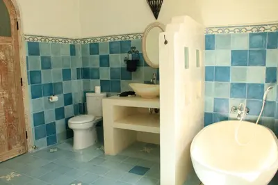 a blue tiled bathroom with a sink and a toilet at M-Apartment in Badung