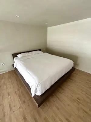 a bedroom with a large bed with white sheets at Olive Athena Guesthouse in Seminyak