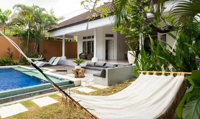 a hammock in front of a house with a pool at Villa VITA in Seminyak