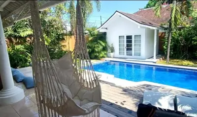 a couple of hammocks sitting next to a swimming pool at Villa VITA in Seminyak