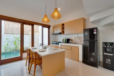 a kitchen with wooden cabinets and a black refrigerator at 3BR Villa Taman Seminyak 27 - Short Drive to Beach in Seminyak