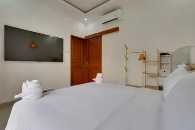 a bedroom with a large white bed with a tv on the wall at 3BR Villa Taman Seminyak 27 - Short Drive to Beach in Seminyak