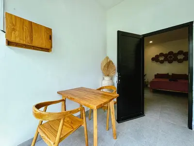 a wooden table and two chairs in a room at Soane Summer House by AGATA in Seminyak