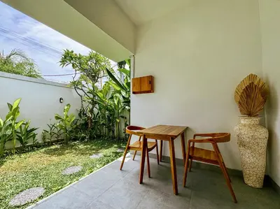 a table and two chairs and a vase on a patio at Soane Summer House by AGATA in Seminyak