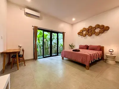 a bedroom with a bed and a table and a window at Soane Summer House by AGATA in Seminyak