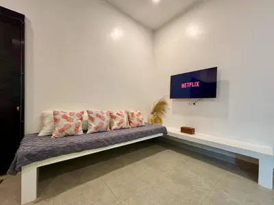 a couch in a room with a tv on the wall at Soane Summer House by AGATA in Seminyak