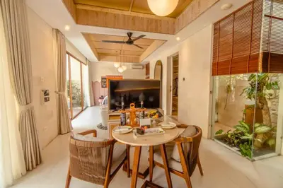 a dining room with a table and chairs and a television at Emica Peaceful Royal 1 BR Pool Villa With Bathtub in Legian