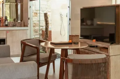 a living room with a table and chairs and a tv at Emica Peaceful Royal 1 BR Pool Villa With Bathtub in Legian