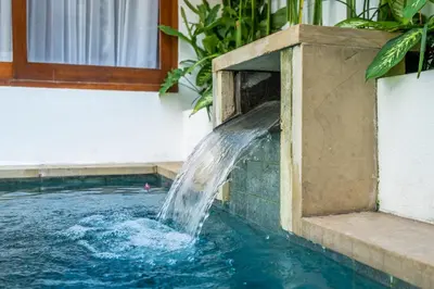 a water fountain in a swimming pool at Sunset Max Villa in Seminyak