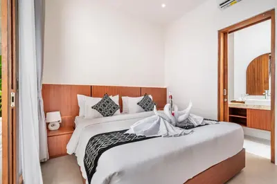 a bedroom with a large white bed and a sink at Sunset Max Villa in Seminyak