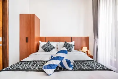 a bedroom with a bed with blue and white pillows at Sunset Max Villa in Seminyak