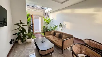 a living room with a couch and chairs and plants at Villa Harmaka 2 in Kerobokan