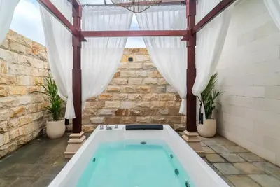 a hot tub in a room with a stone wall at Villa nia gray 1 in Seminyak