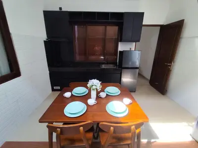 a kitchen with a wooden table with plates and flowers on it at Royal villa nusa dua quiet 2BR with public pool in Nusa Dua