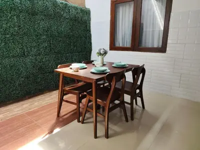 a dining room table with chairs and a table and a window at Royal villa nusa dua quiet 2BR with public pool in Nusa Dua
