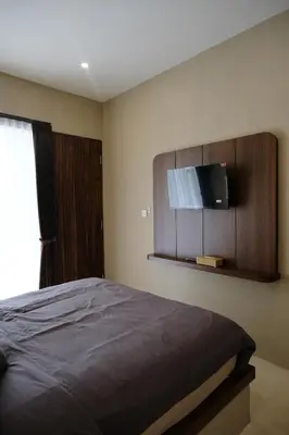 a bedroom with a bed with a flat screen tv on the wall at Avaya Boutique Hostel by Ayodya Beach Inn in Legian