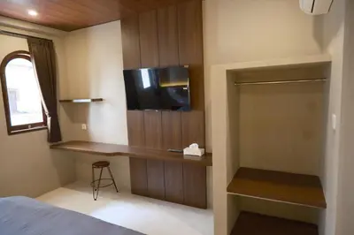 a bedroom with a bed and a tv on a wall at Avaya Boutique Hostel by Ayodya Beach Inn in Legian