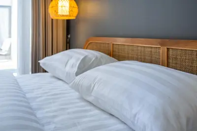 a bed with white sheets and pillows next to a window at Casa Benita 2 Villa Seminyak in Seminyak