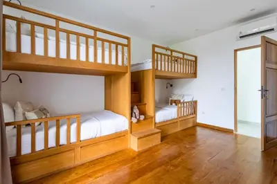 two bunk beds in a room with wooden floors at Ashlyn Elegant 4 BR Private Pool Villa in Canggu