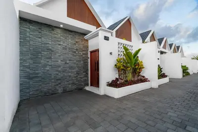 a row of white houses with plants in a courtyard at Villa Paoua by BaliSuperHost in Seminyak