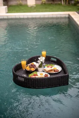 a table with food and drinks in a swimming pool at Villa Amani Seminyak in Seminyak