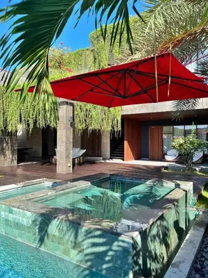 a red umbrella is over a swimming pool at Villa Nishiki 5-Bedroom Private Villa in Seminyak in Seminyak
