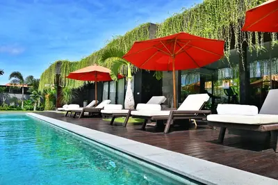 a pool with chairs and umbrellas next to a building at Villa Nishiki 5-Bedroom Private Villa in Seminyak in Seminyak