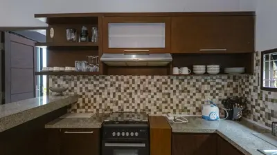 a kitchen with wooden cabinets and a stove top oven at 3BR Private Pool Villa in Central Seminyak - Walk to Cafés & Shops in Seminyak