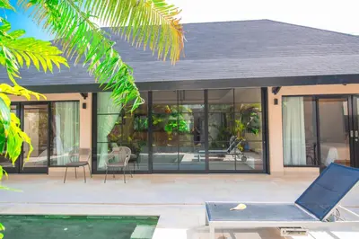 a house with glass doors and a chair on a patio at Amazing Private Pool Villa 2BR in Seminyak Bali in Kerobokan
