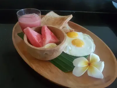 a plate of food with eggs and toast and a drink at Seminyak Villa in Seminyak