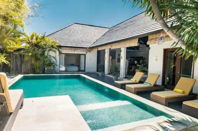 a swimming pool with chairs and a house at Seminyak Villa in Seminyak