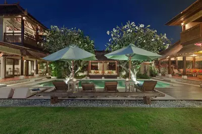 a house with a swimming pool with chairs and umbrellas at Luxury 6-bedroom Villa in Seminyak in Seminyak