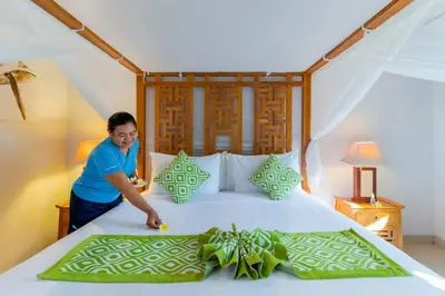 a woman is making a bed in a room at Heart of Seminyak, 2Br, Sleeps 4, Walk to Bintang in Seminyak