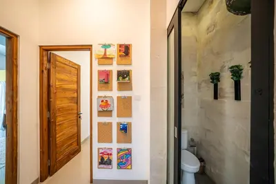 a bathroom with a toilet and pictures on the wall at Villa Tanaka Spacious Family Villa Berawa in Canggu