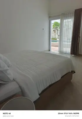 a bedroom with a large white bed with a window at Khrisna Sanur Villa in Pesanggaran