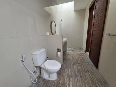 a bathroom with a white toilet and a mirror at Vila Hokyusa in Kerobokan