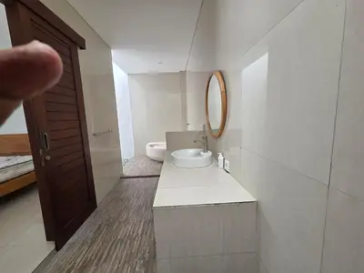 a bathroom with a toilet and a sink and a mirror at Vila Hokyusa in Kerobokan