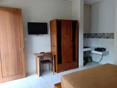 a bedroom with a bed and a wooden door and a desk at Pondok Hokyusa in Seminyak