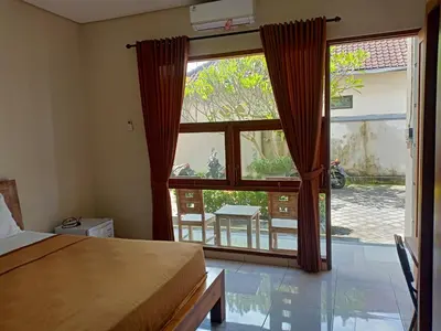 a bedroom with a bed and a large window at Pondok Hokyusa in Seminyak