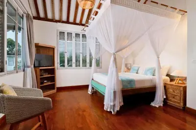 a bedroom with a canopy bed and a television at Dulcinea Spacious 5 BR Private Pool Villa in Jimbaran