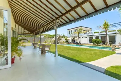 an outdoor patio with tables and chairs and a pool at Dulcinea Spacious 5 BR Private Pool Villa in Jimbaran