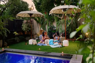 a group of three girls sitting around a pool at Vansari Hotel in Seminyak