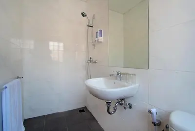 a white bathroom with a sink and a mirror at Vansari Hotel in Seminyak