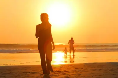 a woman walking on the beach at sunset at Vansari Hotel in Seminyak