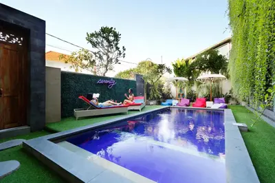 a backyard with a swimming pool and two people laying in a hammock next to at Vansari Hotel in Seminyak