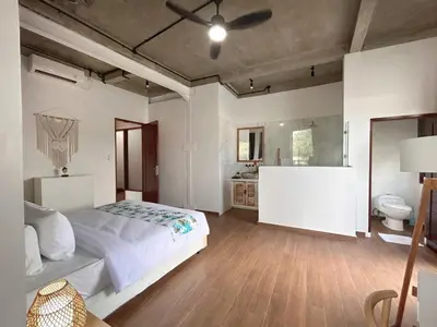a bedroom with a large bed and a bathroom at Uma 2 BR villa with Roof top pool & Enclosed living room in Seminyak