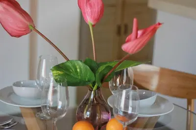 a vase with flowers in it on a table with glasses at Uma 2 BR villa with Roof top pool & Enclosed living room in Seminyak