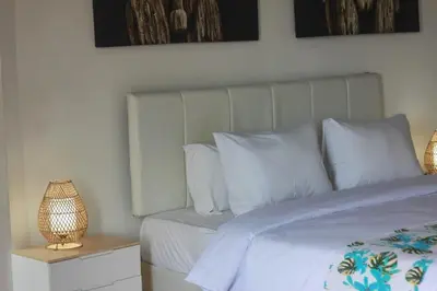 a bedroom with a bed with white sheets and pillows at Uma 2 BR villa with Roof top pool & Enclosed living room in Seminyak