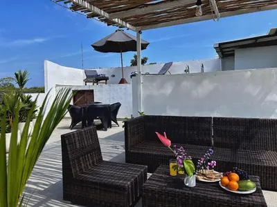 a patio with two chairs and a table and an umbrella at Uma 2 BR villa with Roof top pool & Enclosed living room in Seminyak